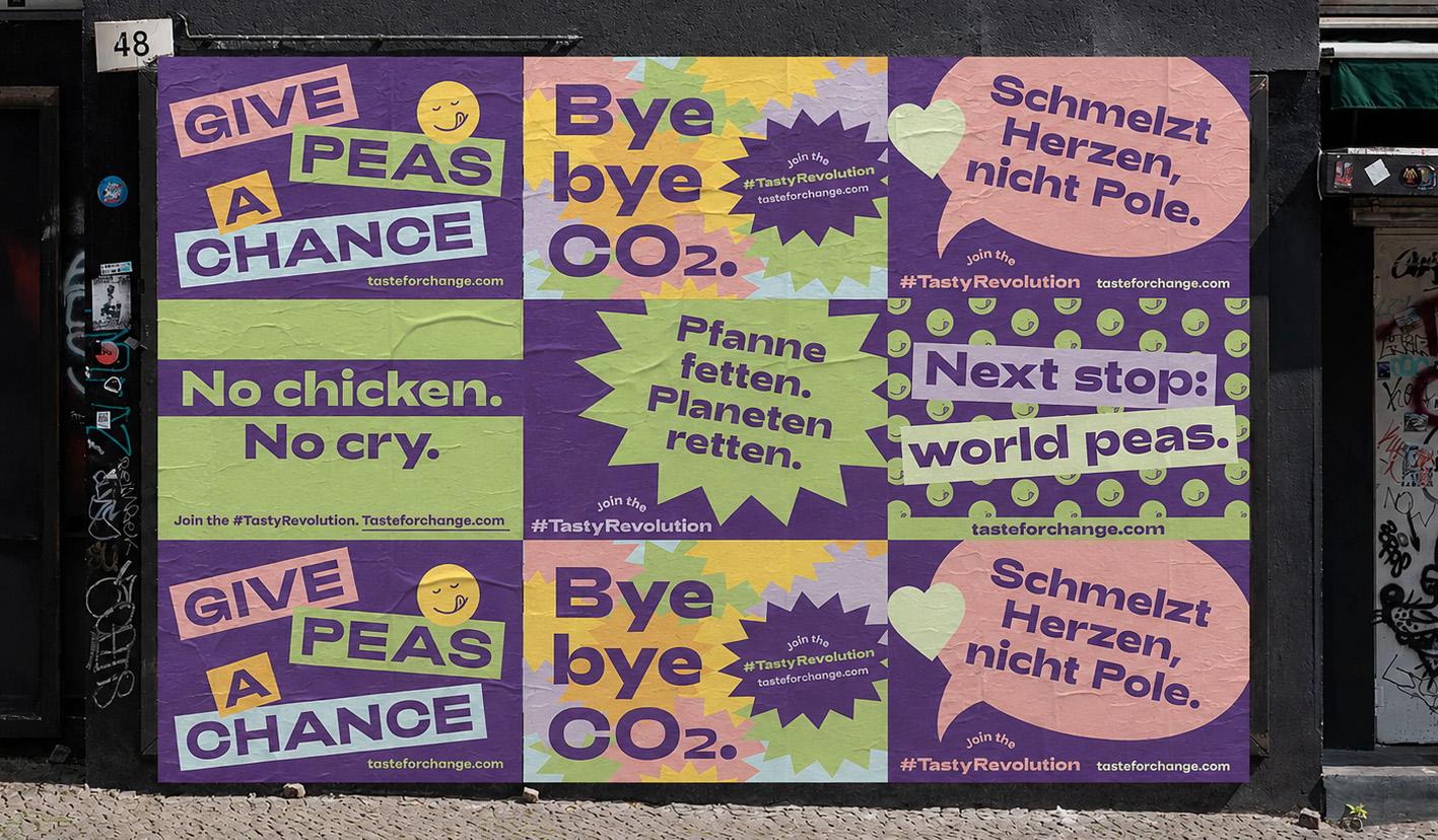 A grid of purple and green Tasty Revolution posters mounted on a building wall, reading 'Give Peas a Chance', 'Bye bye CO2' and more